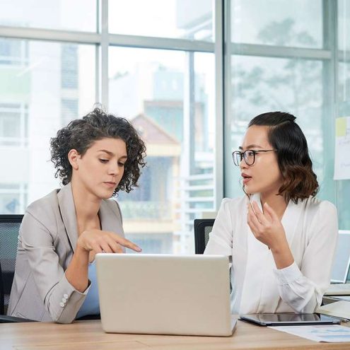 two women talking with a laptop open